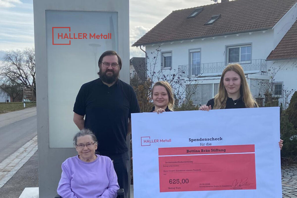 Zu sehen sind von links nach rechts: Eine ältere Dame im Rollstuhl, ein Herr, und zwei junge Mädchen die einen Scheck für die Bettina Bräu Stiftung in der Hand halten.